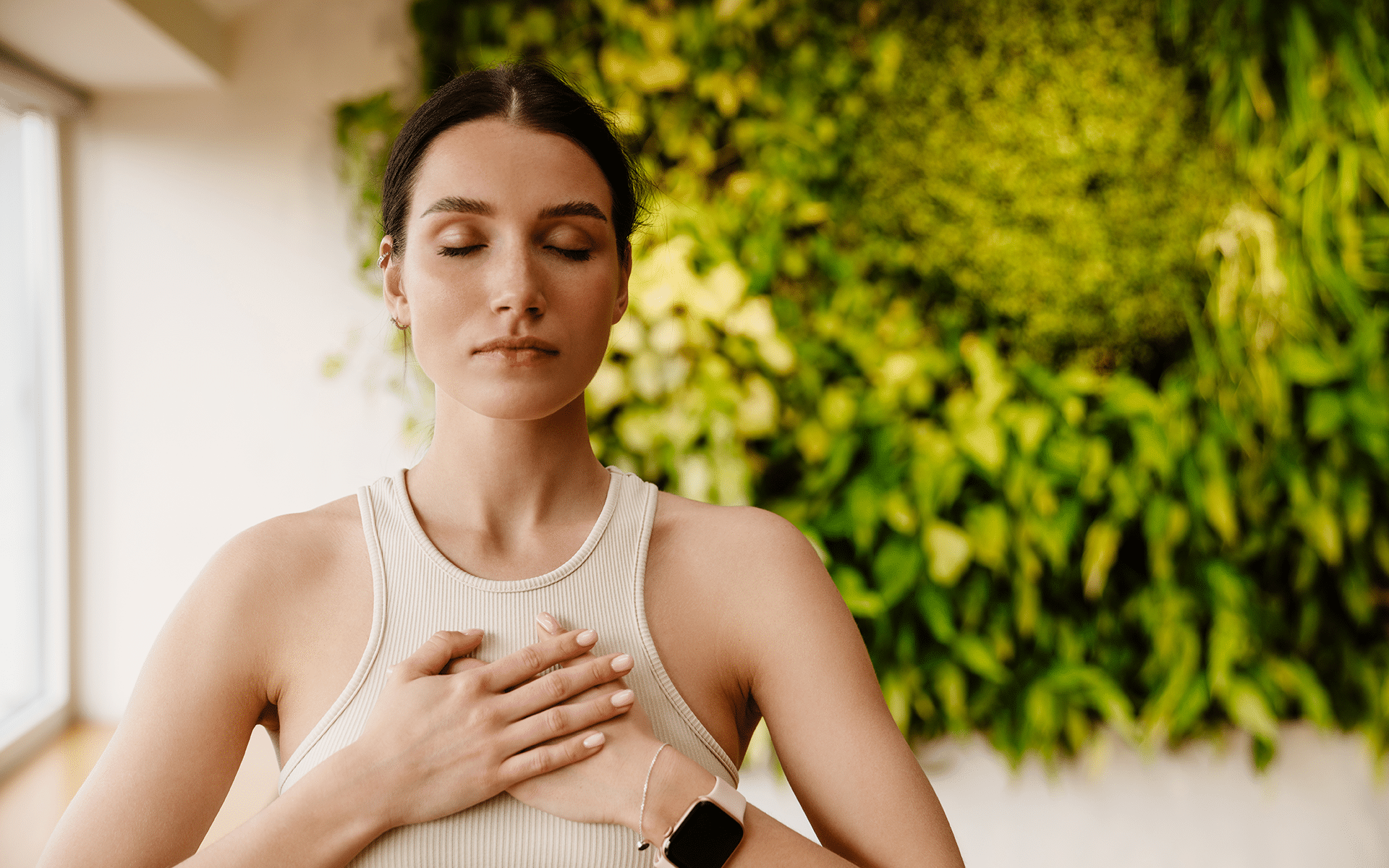 Photo of a white woman with brown hair placing her hands over her heart with her eyes closed and a peaceful expression.